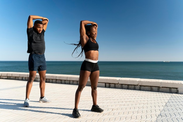 Foto de corpo inteiro do casal americano africano em roupas esportivas aquecendo e treinando