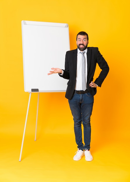 Foto de corpo inteiro do empresário dando uma apresentação no quadro branco sobre amarelo isolado