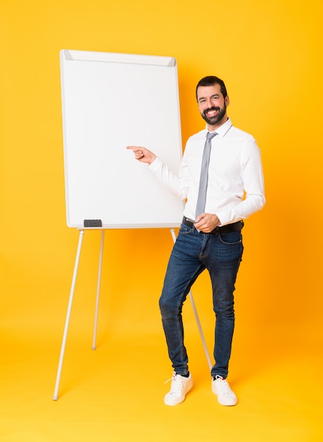 Foto de corpo inteiro do empresário dando uma apresentação no quadro branco sobre o dedo apontando amarelo isolado para o lado