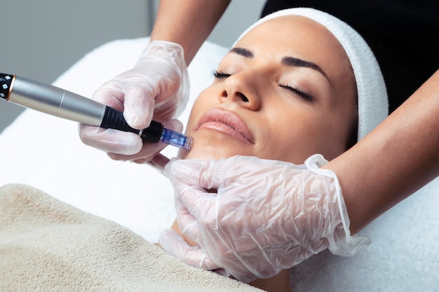 Foto de cosmetologista fazendo injeção de mesoterapia com dermapen no rosto para rejuvenescimento no centro de spa.