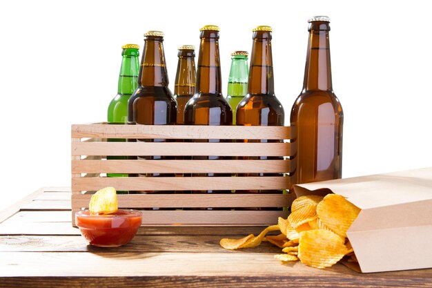 Foto de diferentes garrafas de cerveja cheias sem rótulos e pacotes de papel de batatas fritas em molhos de mesa