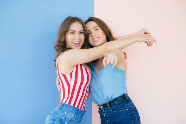 Foto de duas amigas emocionais em pé isoladas sobre fundo colorido