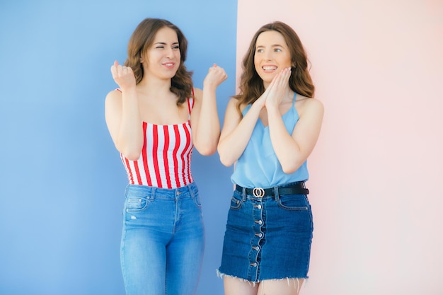 Foto de duas amigas emocionais em pé isoladas sobre fundo colorido