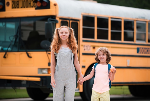 Foto de duas crianças felizes olhando pelas janelas de um ônibus escolar amarelo muito espaço para texto