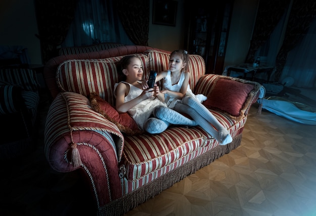 Foto de duas garotas lutando pelo controle remoto da TV no sofá à noite