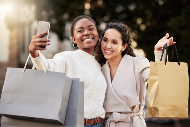 Foto de duas jovens tirando selfies enquanto fazia compras em um ambiente urbano