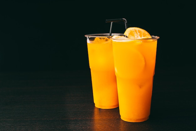 Foto foto de duas limonadas laranja na mesa escura sobre fundo preto