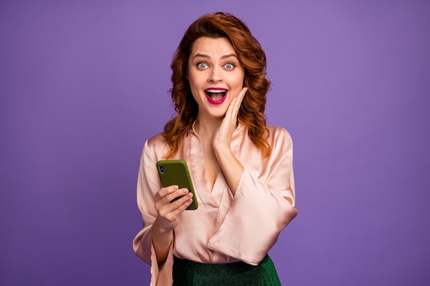 Foto de encantadora senhora louca segurando telefone, boca aberta, mão na bochecha