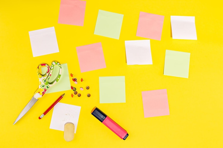 Foto foto de estúdio com fundo amarelo com papel de carta como post-its, lápis, tesoura, borracha e marcador