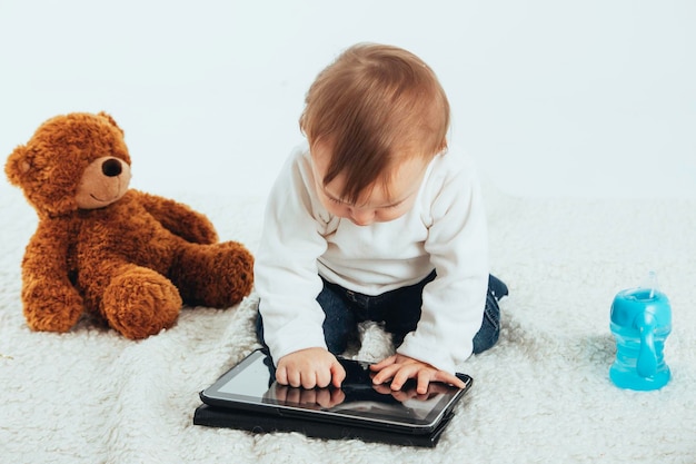 Foto de estúdio com fundo branco de um bebê olhando para a tela de um tablet