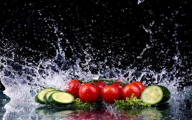 Foto de estúdio com movimento congelado de tomate cereja e fatias de pepino