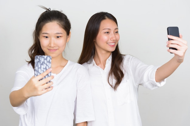 Foto de estúdio de duas jovens coreanas lindas amigas juntas contra um fundo branco