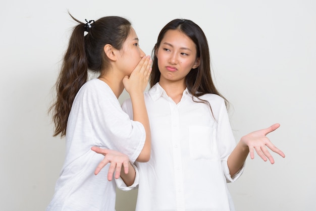 Foto de estúdio de duas jovens coreanas lindas amigas juntas contra um fundo branco