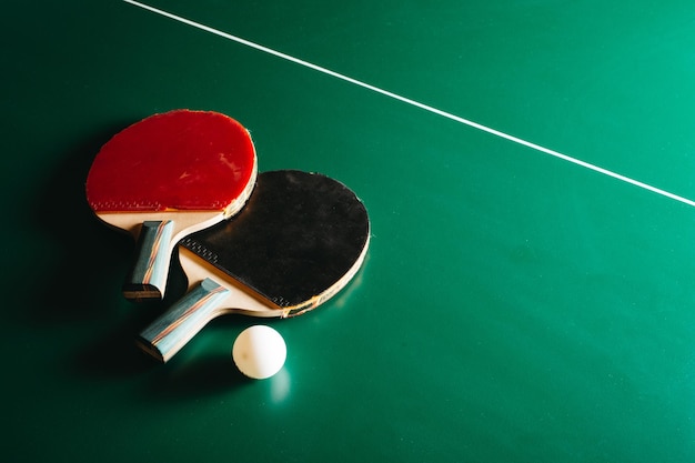 Foto foto de estúdio de duas raquetes de pingue-pongue e uma bola estão na mesa de jogo verde