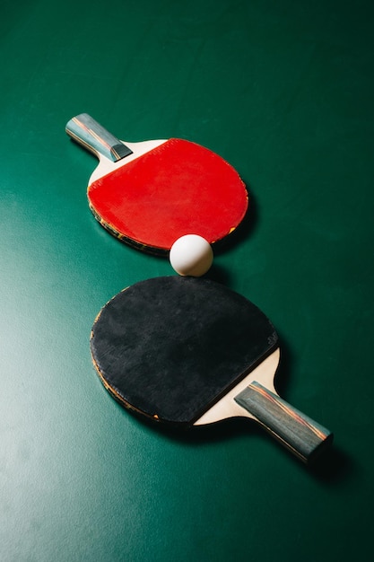 Foto foto de estúdio de duas raquetes de pingue-pongue e uma bola estão na mesa de jogo verde