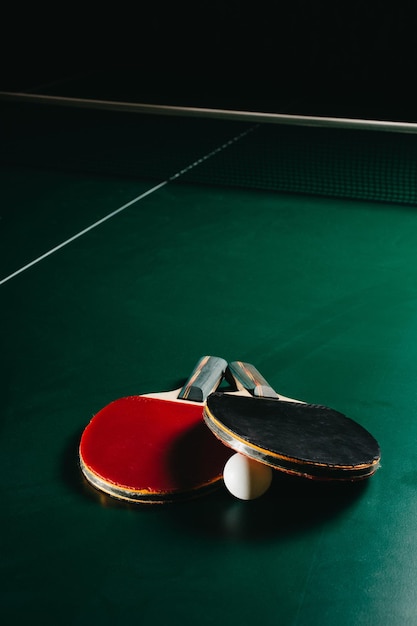 Foto foto de estúdio de duas raquetes de pingue-pongue e uma bola estão na mesa de jogo verde