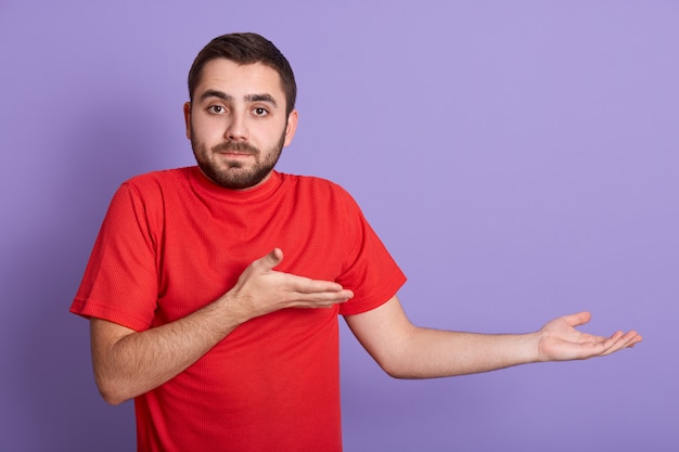 Foto de estúdio de homem descontente, vestindo camiseta casual vermelha.