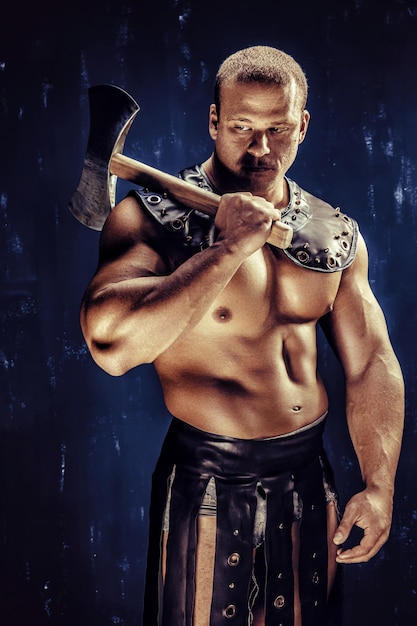 Foto de estúdio de homem guerreiro antigo musculoso posando com machado