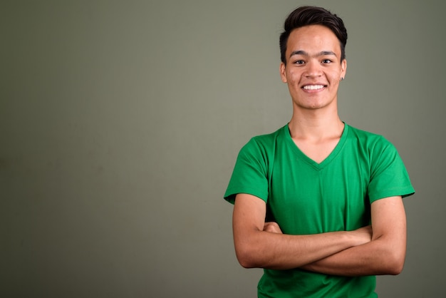Foto de estúdio de jovem adolescente vestindo uma camisa verde contra cor