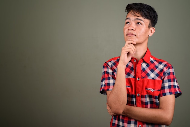 Foto de estúdio de jovem adolescente vestindo uma camisa xadrez vermelha