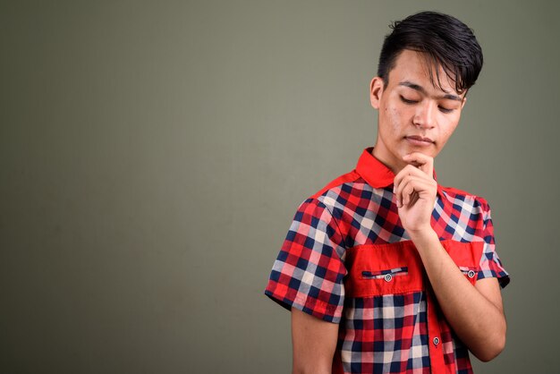 Foto de estúdio de jovem adolescente vestindo uma camisa xadrez vermelha