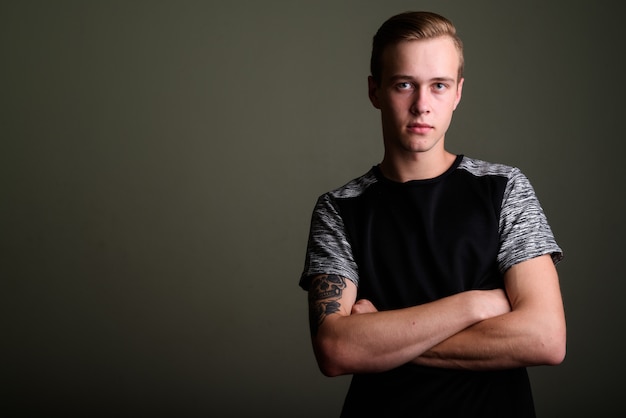 Foto de estúdio de jovem bonito com cabelo loiro contra um fundo colorido