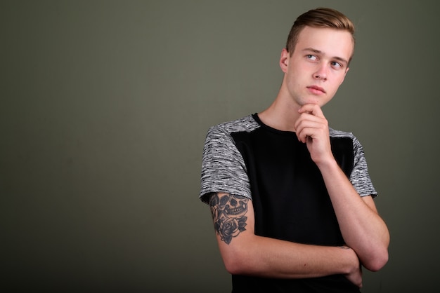 Foto de estúdio de jovem bonito com cabelo loiro contra um fundo colorido