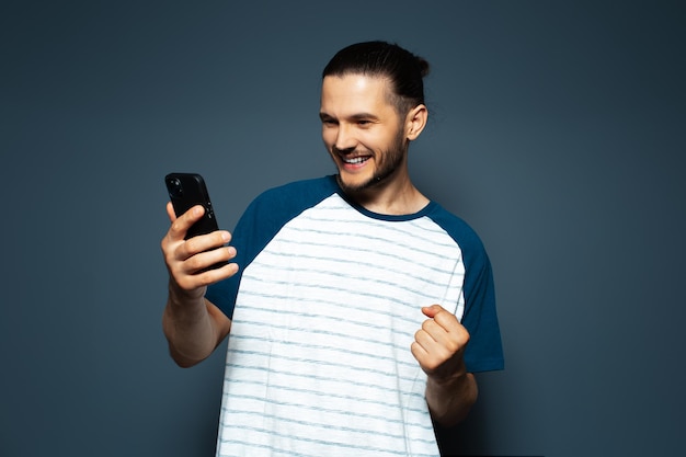 Foto de estúdio de jovem confiante sorridente segurando um smartphone