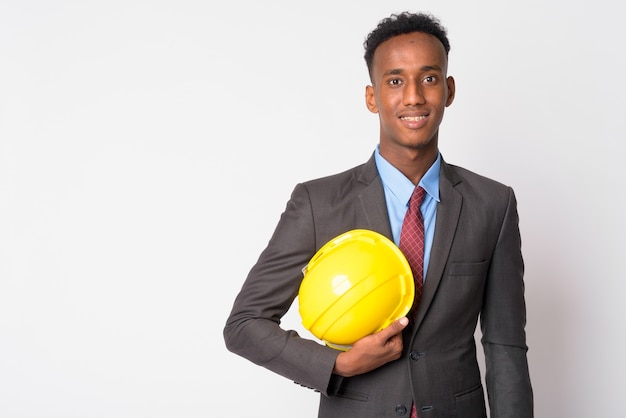 Foto de estúdio de jovem empresário bonito com cabelo afro, vestindo terno contra branco