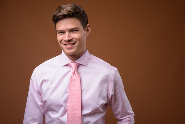 Foto de estúdio de jovem empresário bonito com camisa rosa