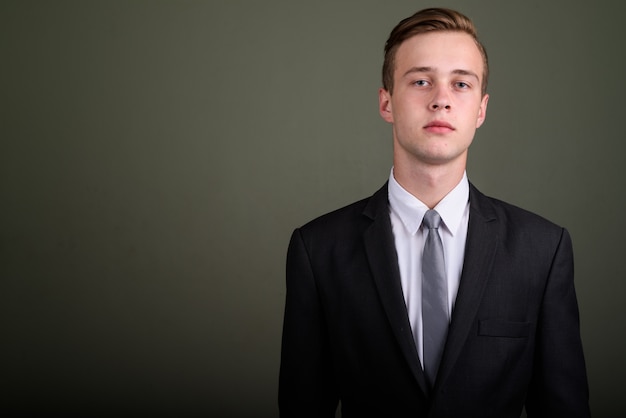 Foto de estúdio de jovem empresário bonito usando terno contra um fundo colorido