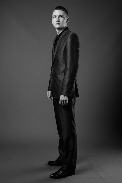 Foto de estúdio de jovem empresário vestindo terno contra uma parede cinza