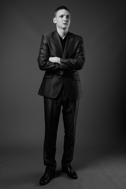 Foto de estúdio de jovem empresário vestindo terno contra uma parede cinza