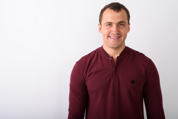 Foto de estúdio de jovem feliz e musculoso sorrindo contra ba