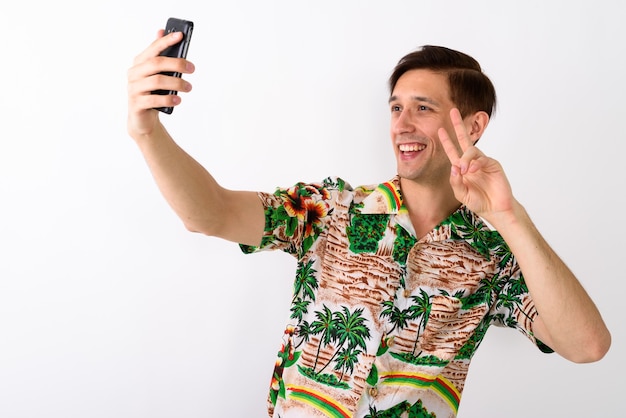 Foto de estúdio de jovem turista feliz sorrindo enquanto dava peac