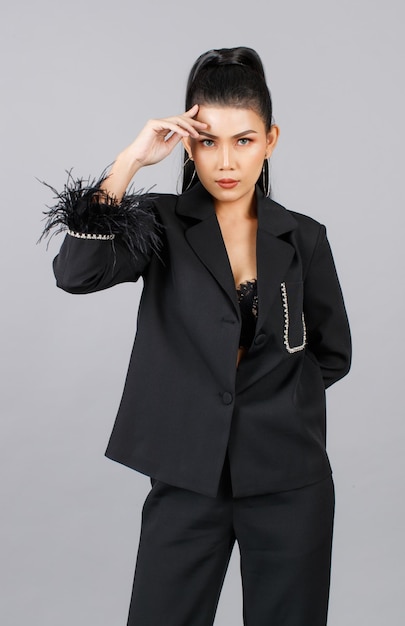 Foto de estúdio de recorte isolado de retrato do modelo de moda elegante feminina asiática milenar em terno de pele preto casual elegante em pé, olhando para a câmera em fundo cinza
