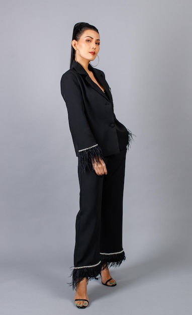 Foto de estúdio de recorte isolado de retrato do modelo elegante feminino milenar asiático em terno de pele elegante casual preto em pé posando, coloque a mão no bolso da calça, olhe para a câmera no fundo cinza