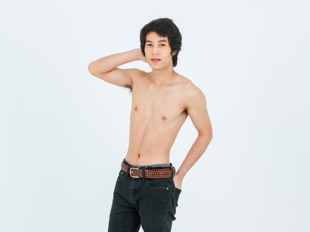Foto de estúdio de recorte isolado retrato de asiático jovem bonito confiante magro magro musculoso adolescente sem camisa modelo masculino em pé posando segurando a mão no bolso da calça jeans no fundo branco