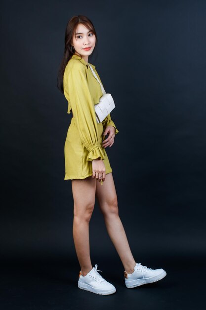 Foto de estúdio de retrato de empresária feminina de moda urbana asiática em roupa casual de top cropped carregando bolsa, olhe para a câmera no fundo preto.