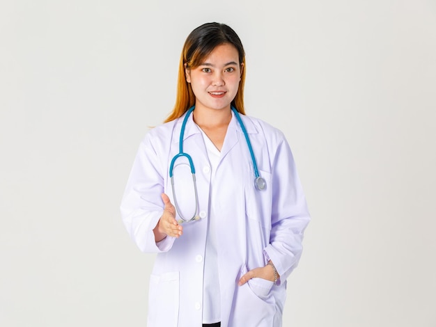 Foto de estúdio de retrato do médico clínico profissional bem sucedido asiático feminino em uniforme de jaleco pendurado estetoscópio em pé no pescoço, sorrindo e dar a mão para apertar.