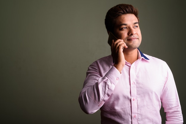 Foto de estúdio de um empresário indiano vestindo uma camisa rosa contra um fundo colorido