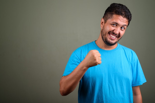 Foto de estúdio de um homem barbudo vestindo uma camisa azul contra cores