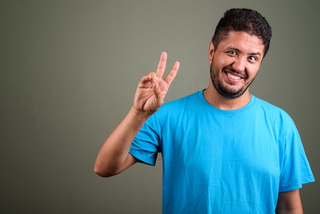 Foto de estúdio de um homem barbudo vestindo uma camisa azul contra cores