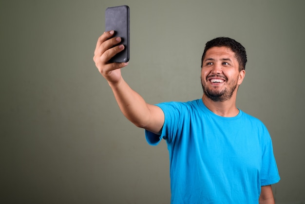 Foto de estúdio de um homem barbudo vestindo uma camisa azul contra cores