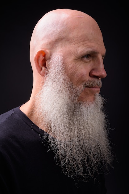 Foto de estúdio de um homem maduro de barba careca contra um fundo preto