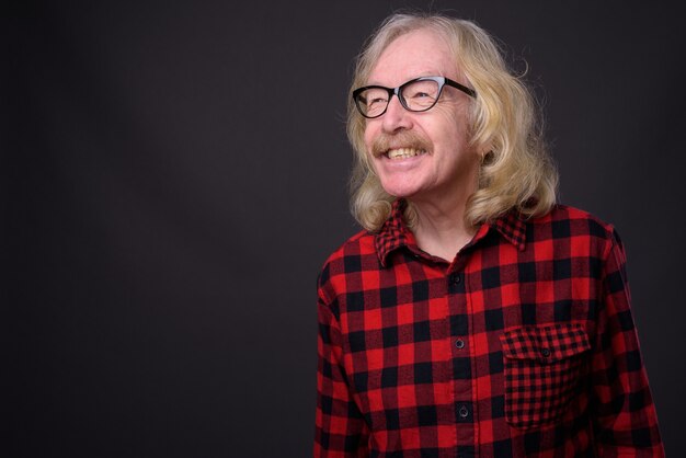 Foto de estúdio de um homem sênior com bigode e camisa quadriculada vermelha contra um fundo cinza