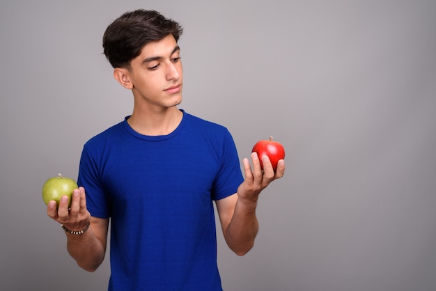 Foto de estúdio de um jovem adolescente persa bonito contra um fundo cinza