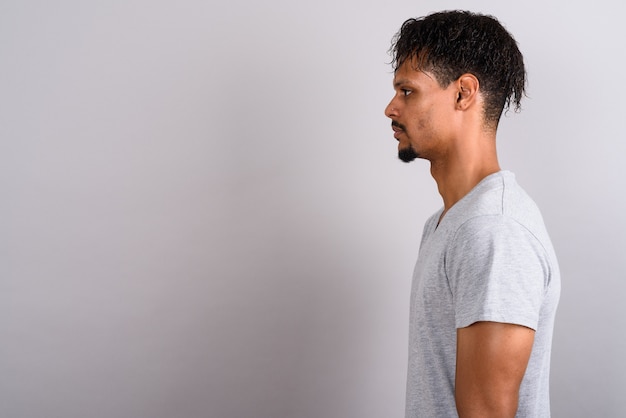 Foto de estúdio de um jovem africano bonito barbudo vestindo uma camisa cinza contra um fundo cinza