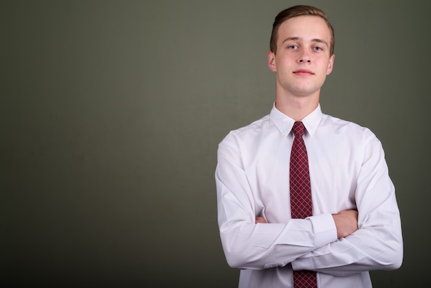 Foto de estúdio de um jovem empresário bonito com cabelo loiro contra um fundo colorido