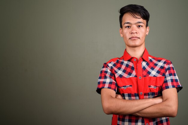 Foto de estúdio de um jovem indiano adolescente vestindo uma camisa xadrez vermelha